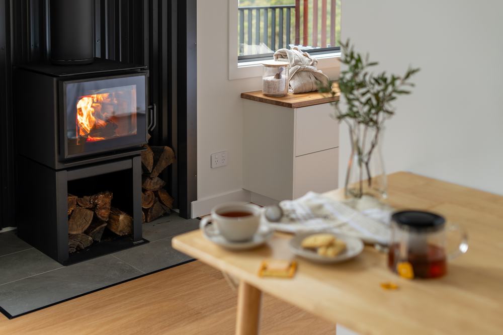 Wood fire burning beside a table set with tea inside a Breath cabin.