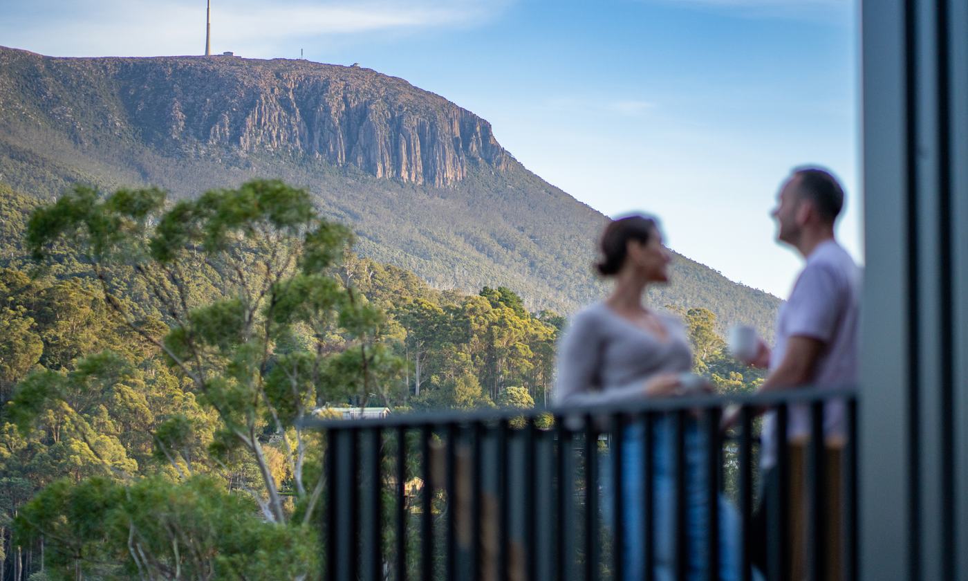 Couple enjoying the view of kunanyi/Mount Wellington from a Breath cabin balcony.