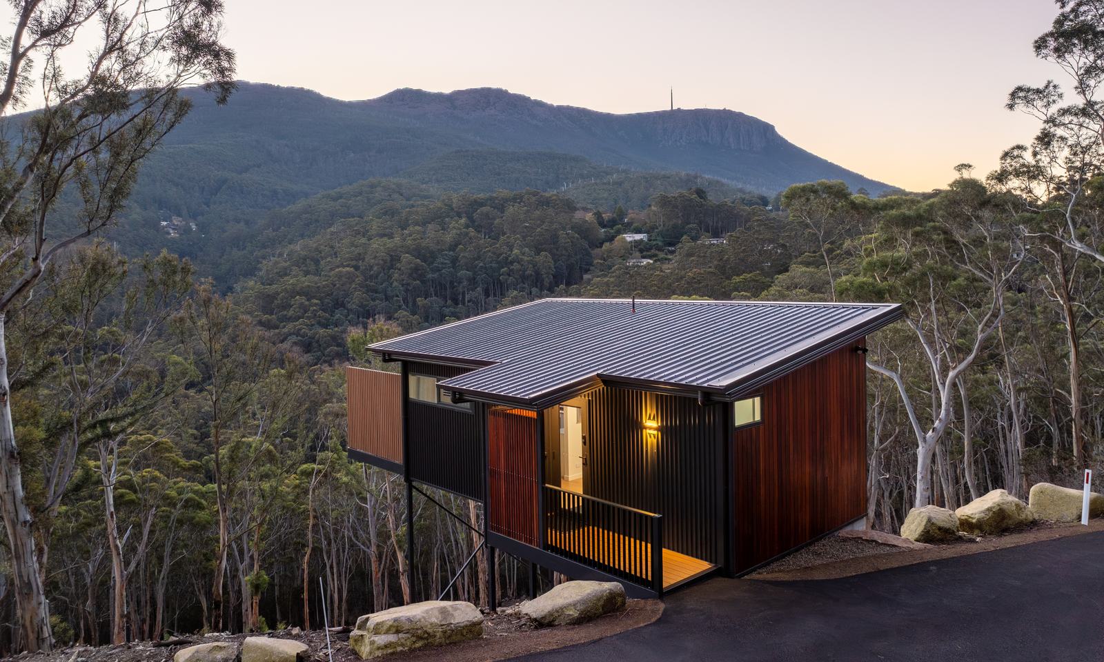 Breath cabin overlooking the forested slopes of kunanyi/Mount Wellington at dusk.