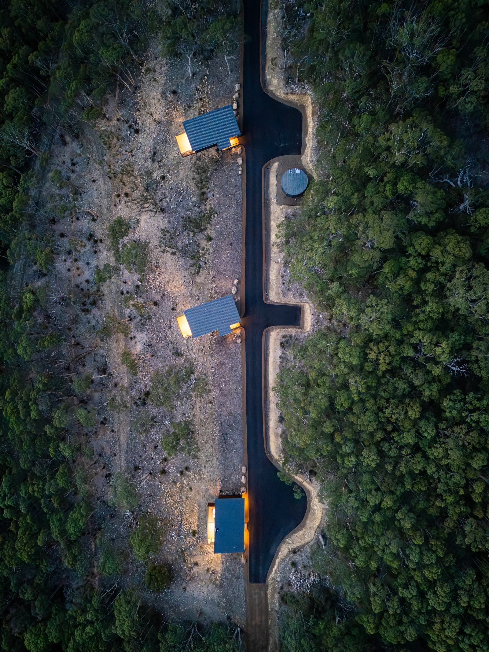 Overhead aerial shot of 3 hillside cabins in the forest