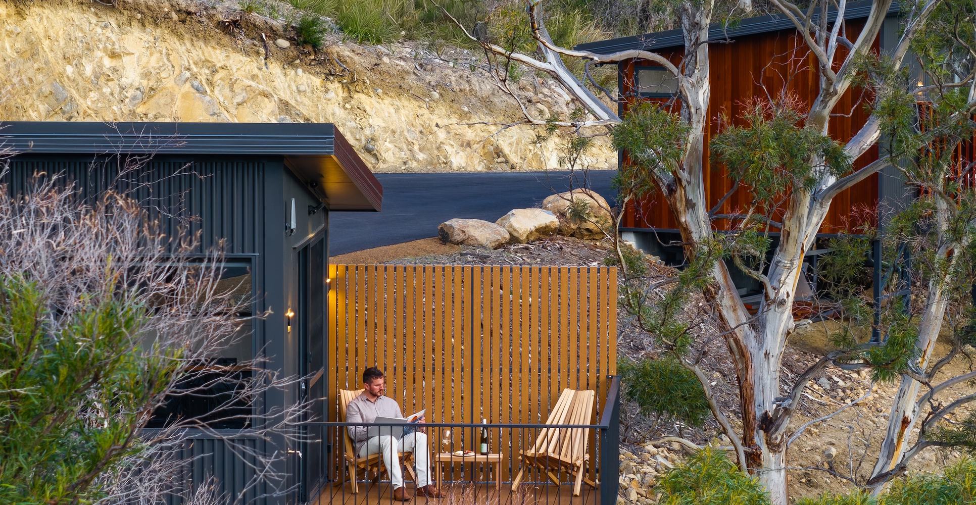 Person sitting on deck amongst gumtrees overlooking the forest