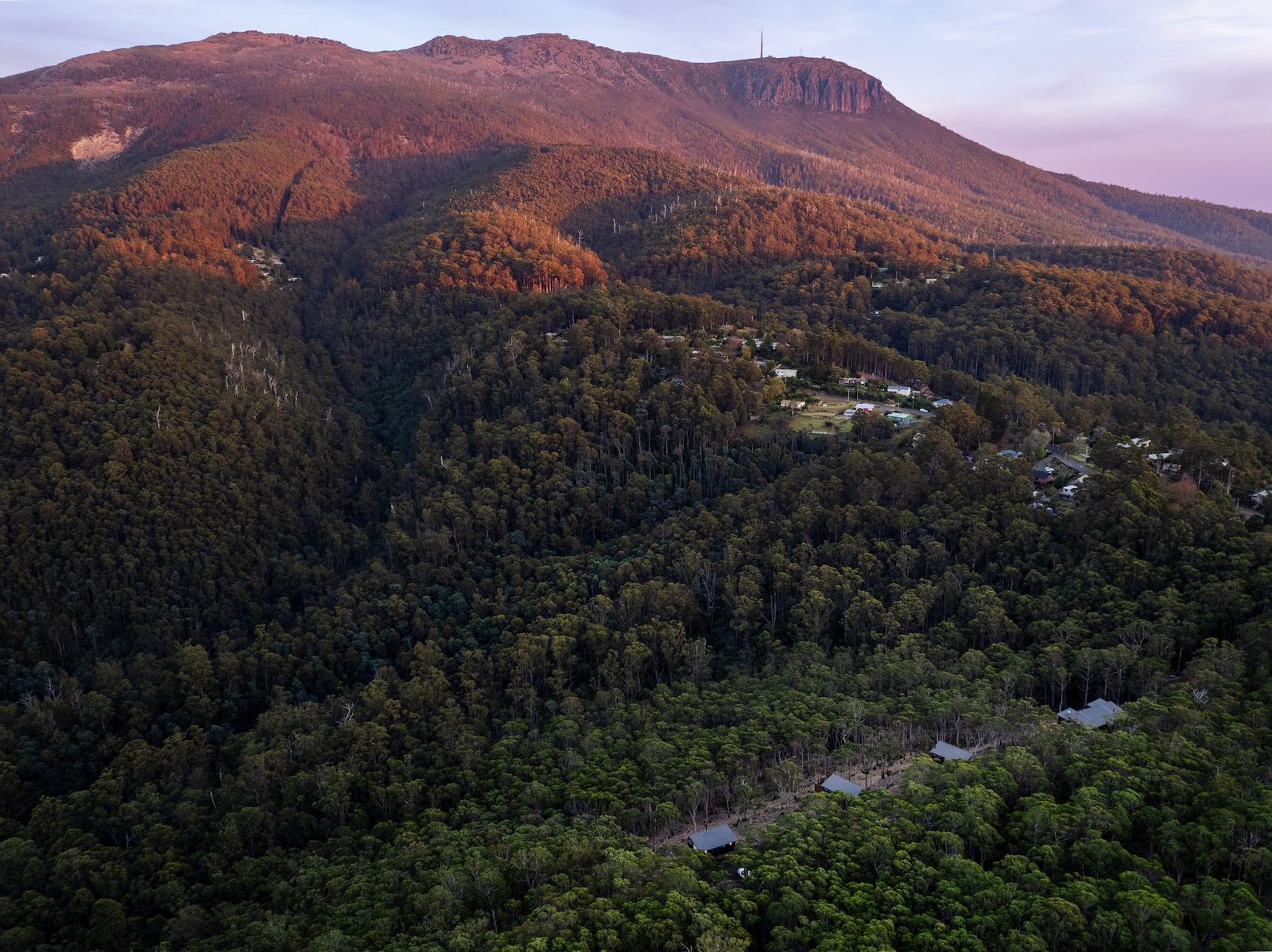 Aerial shot of 3 hillside cabins overlooking kunanyi