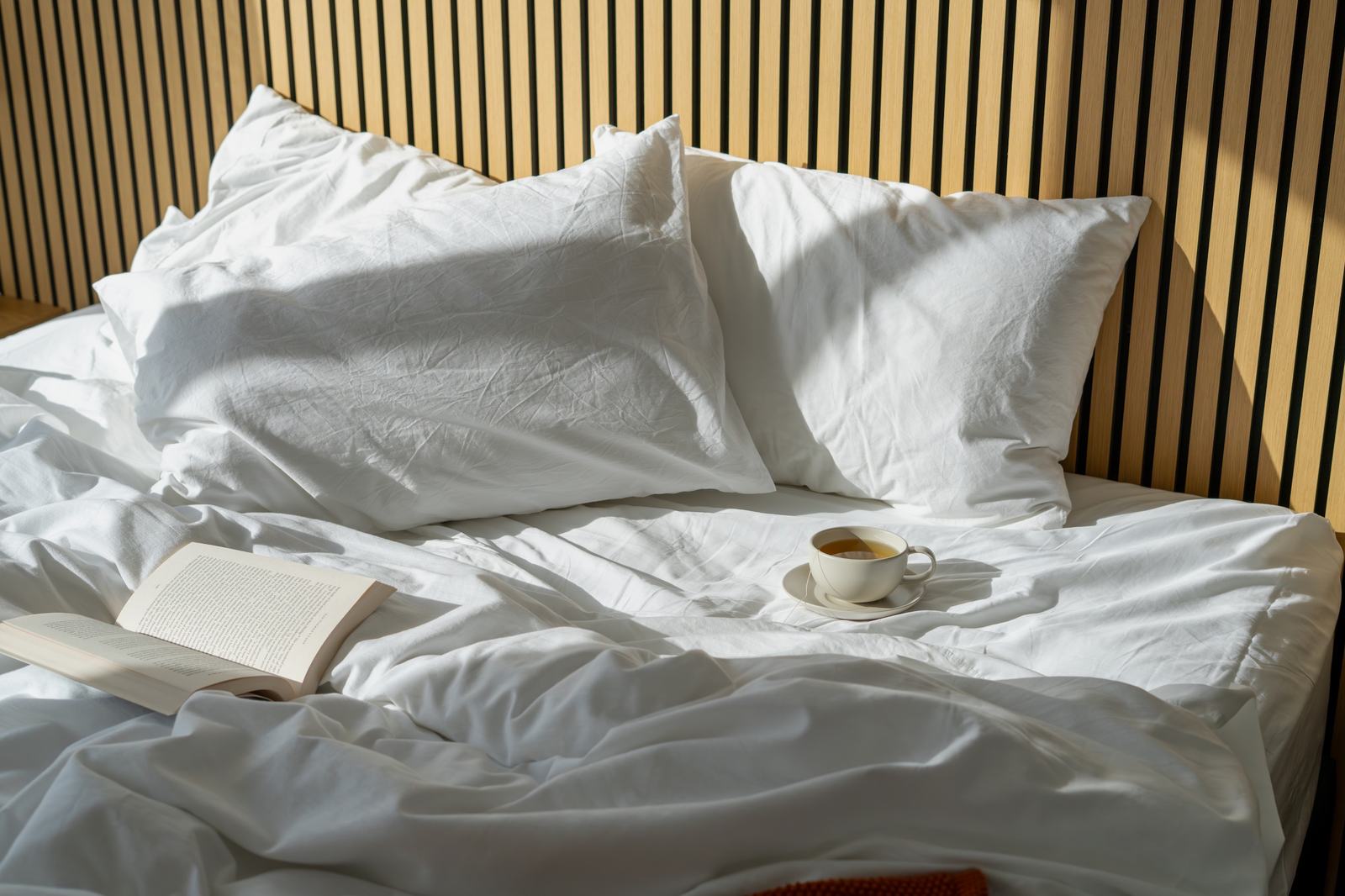 Comfortable bed with pillows tea and book