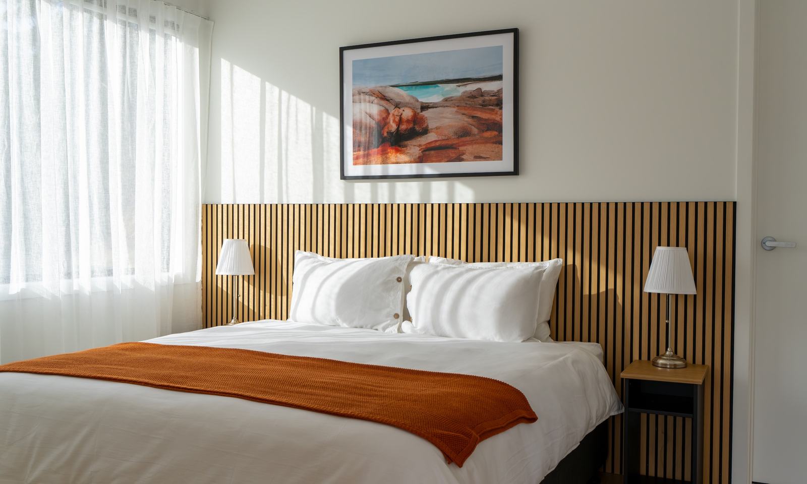 Ironbark bedroom showing bed soft curtains and artwork