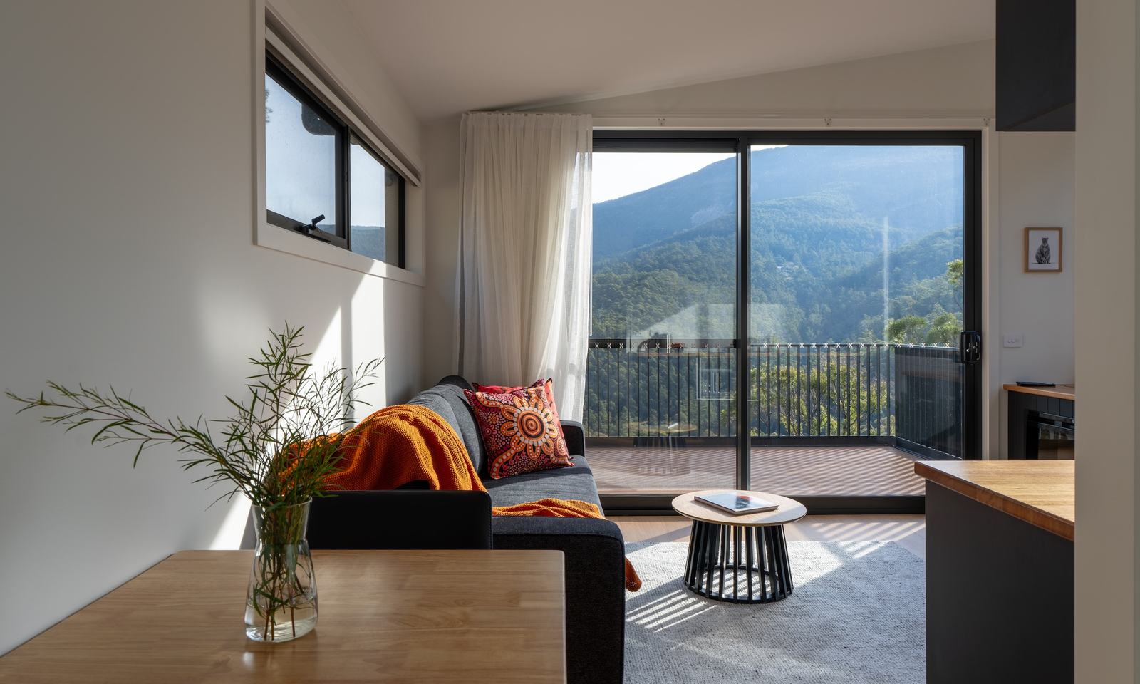 Living area of Ironbark cabin with cushions and blankets with view to mountains