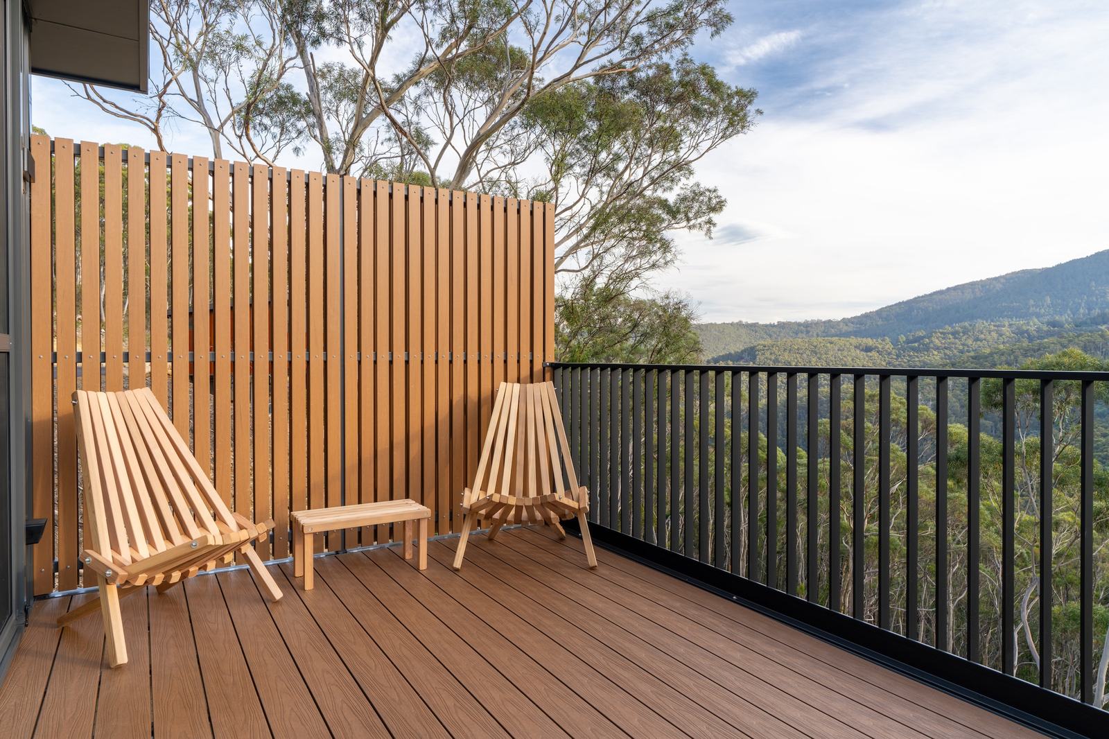 Sunny outdoor deck of ironbark cabin overlooking forest