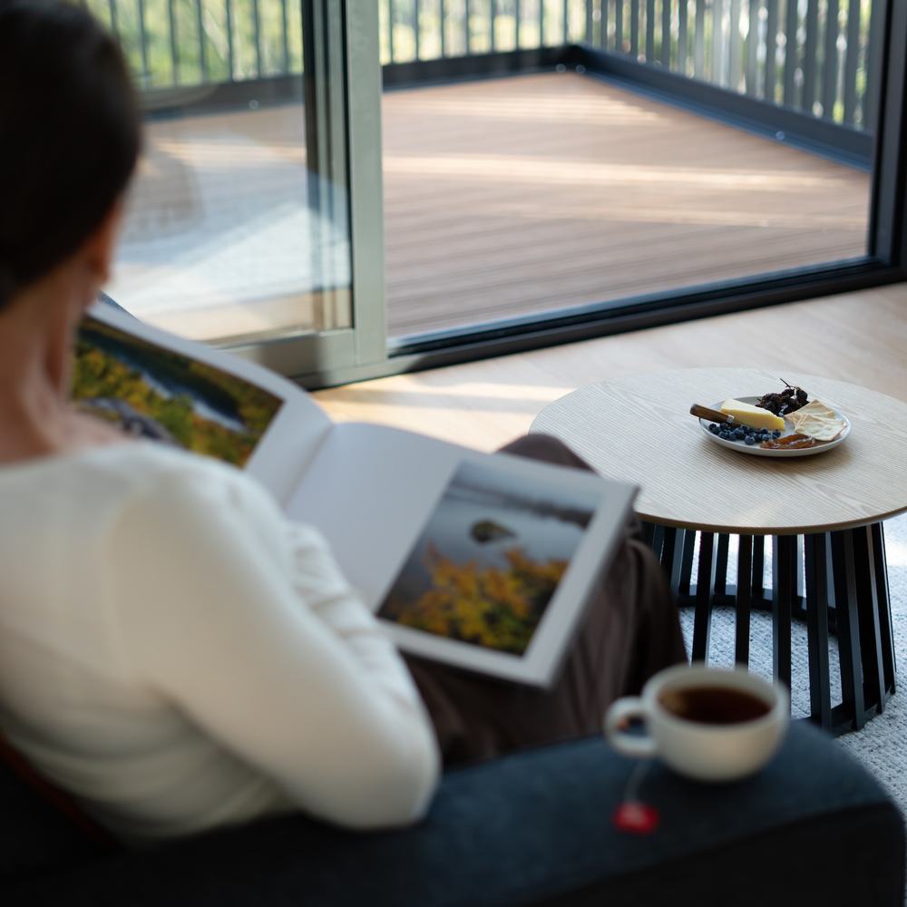 Person reading a book with tea and cheese board on coffee table