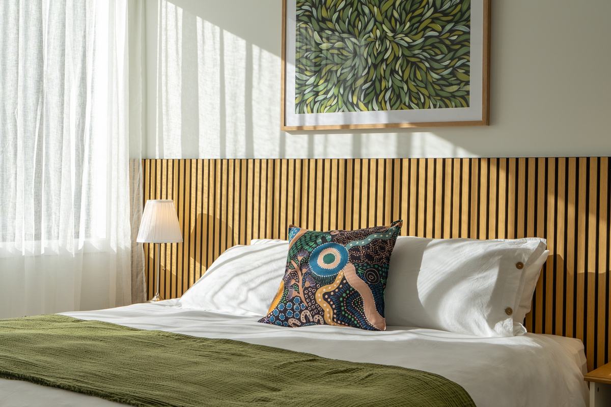 Comfortable bed with green design features and matching artwork on wall