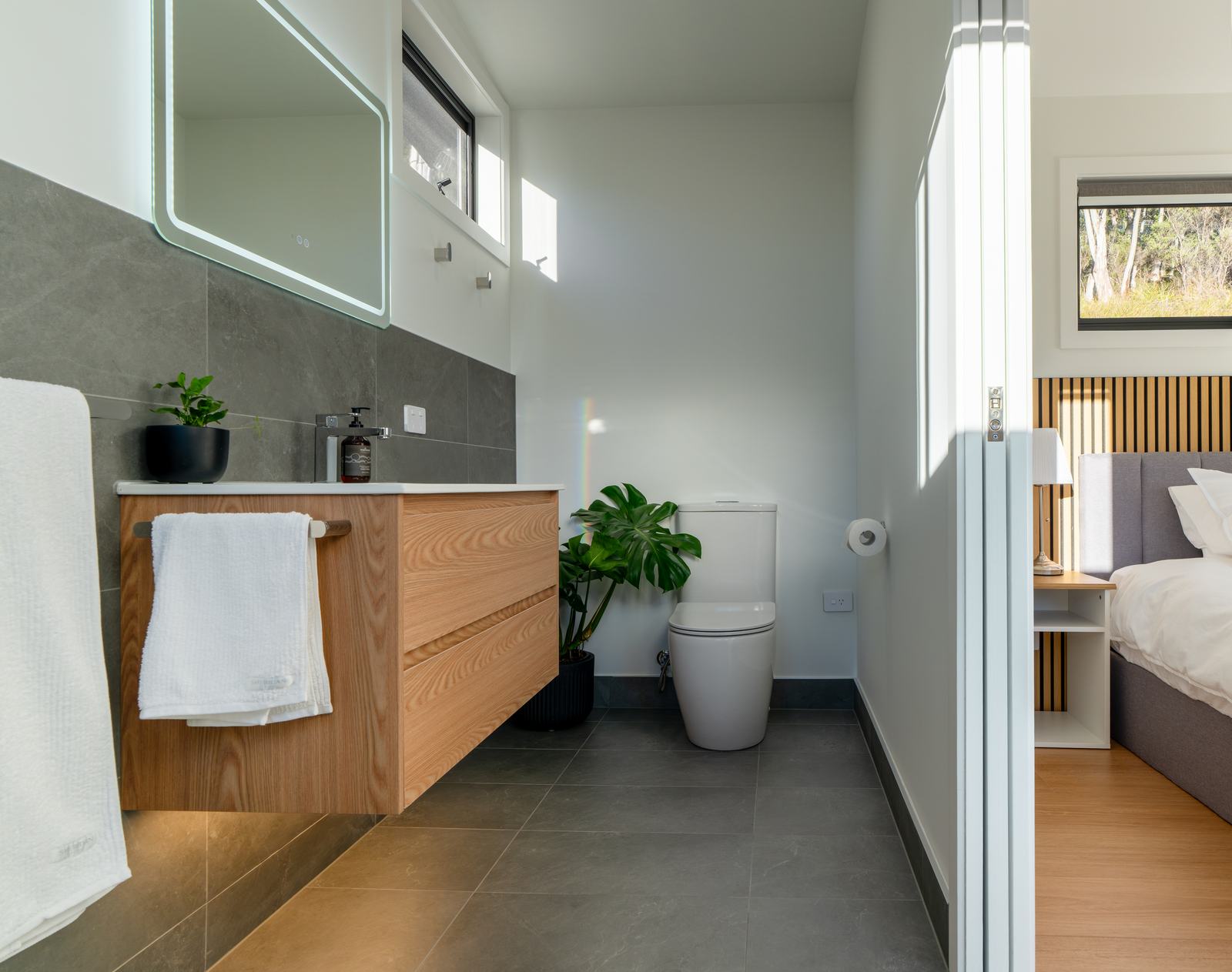 Bathroom of stillwater cabin showing vanity, mirror, toilet and indoor plants