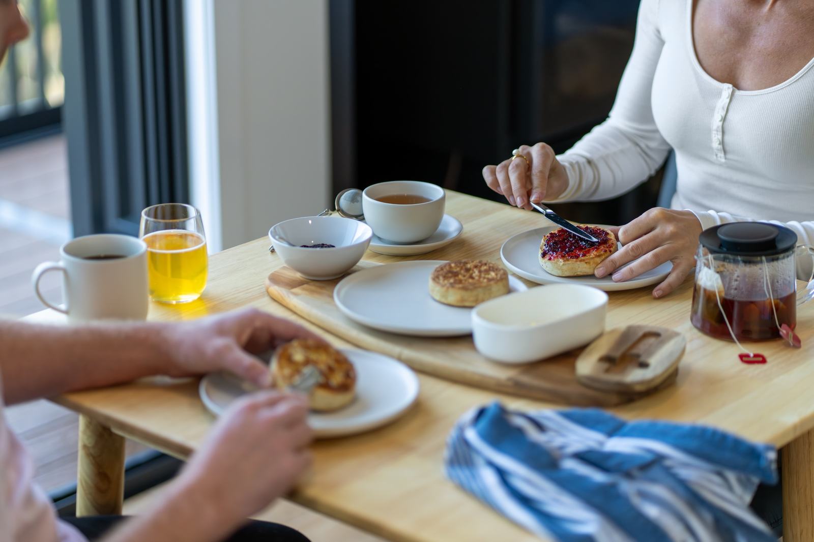 People sitting at table to eat breakfast of tea and sourdough crumpets