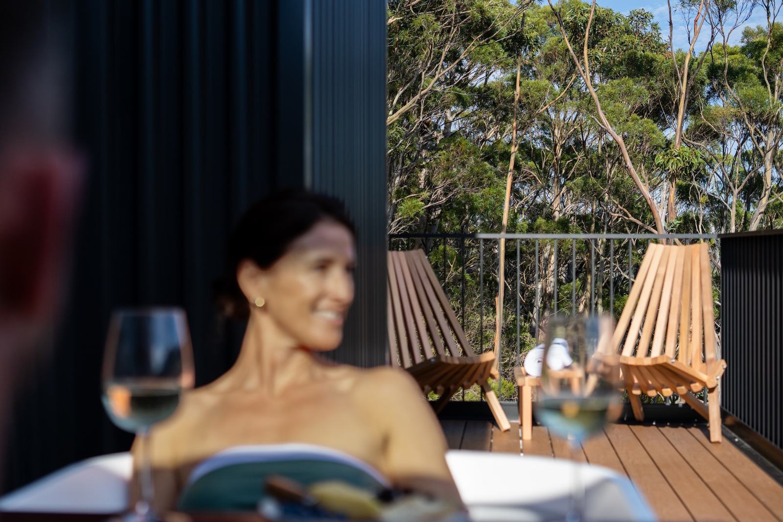 Person in outdoor bath smiling and looking out to the view