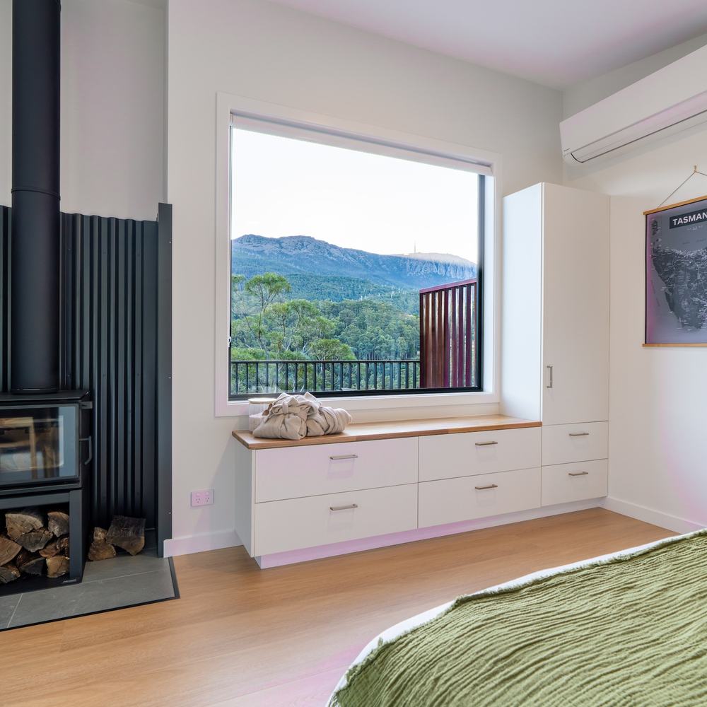 Bedroom with fireplace looking out of large window to forest and mountain
