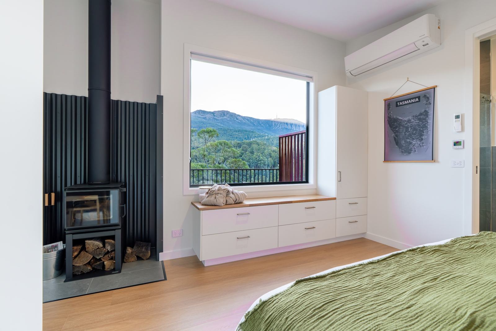 Bedroom with fireplace looking out of large window to forest and mountain