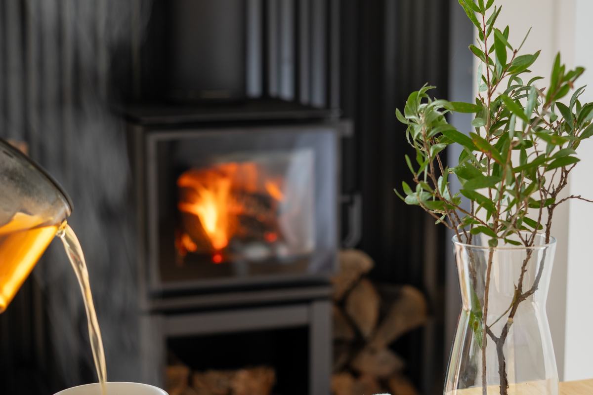 Warm fireplace in the background with hot tea being poured and biscuits on table