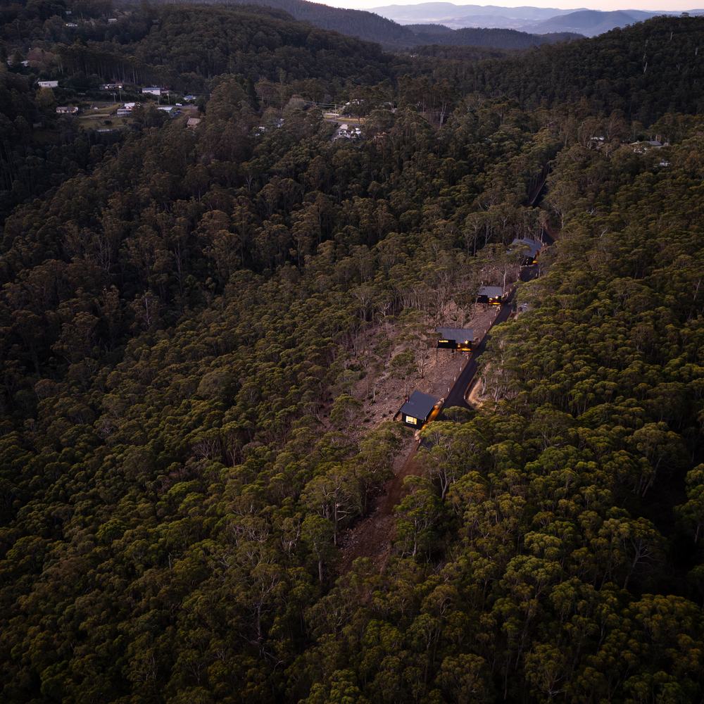 Aerial view of the Breath cabins nestled among the forested hills of Fern Tree, Tasmania.